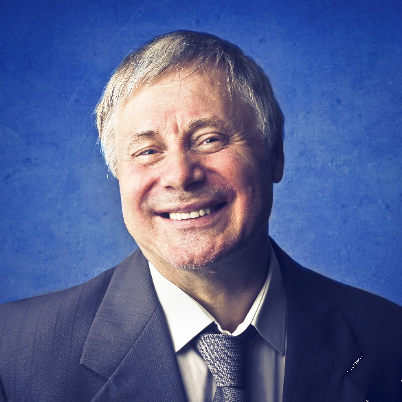A middle-aged man with short gray hair is smiling, dressed in a suit and tie. The background is a textured blue tone, giving a professional and friendly impression.